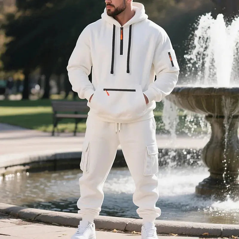 Man wearing a white tracksuit standing in front of a fountain